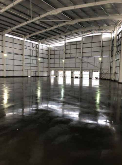 The above photograph shows a jointless steel fibre reinforced industrial concrete floor slab designed and constructed in London. The surface of the concrete floor slab incorporates a dry shake sprinkle topping and surface hardener. The dry shake was supplied by RCR Flooring products and is natural in colour. Level Best Concrete Flooring employ an expert team of concrete finishers to apply and powerfloat the dry shake topping onto the concrete floor slab.